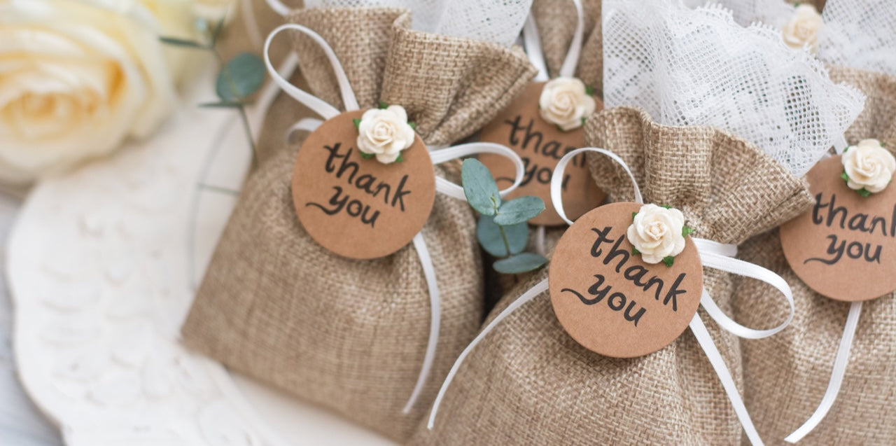 Two long tables decorated with white tablecloth and hessian table runners with white plates and flowers