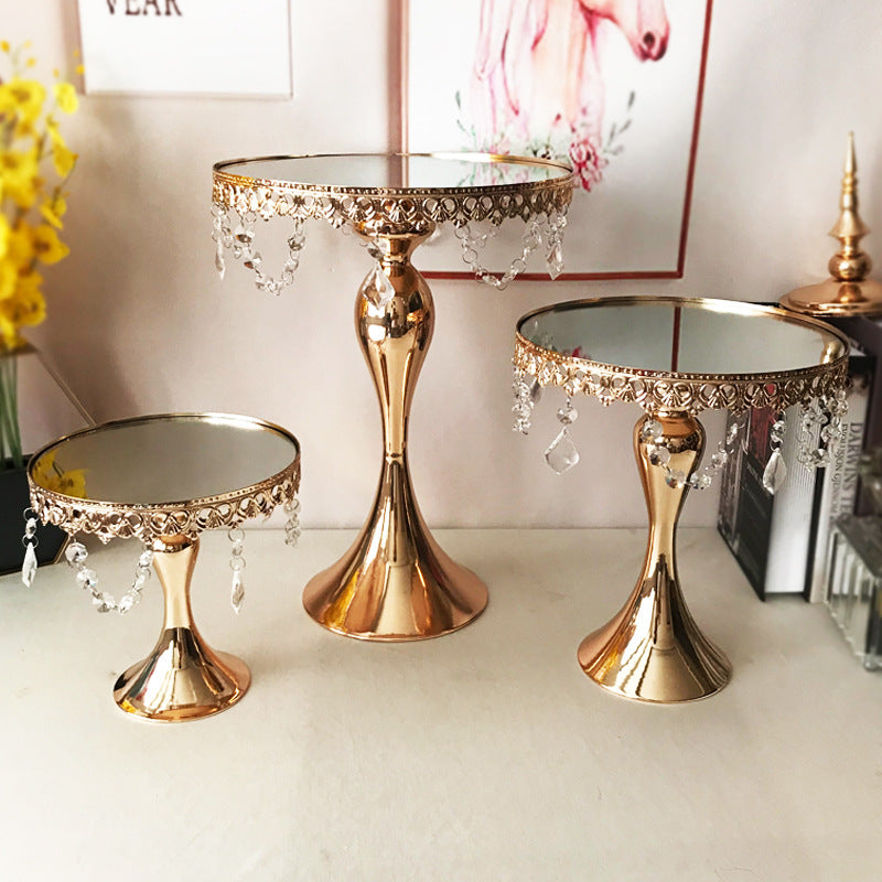 Three rosegold cake stands, all different heights, each cake stand has jewls hanging from edge of each cake stand