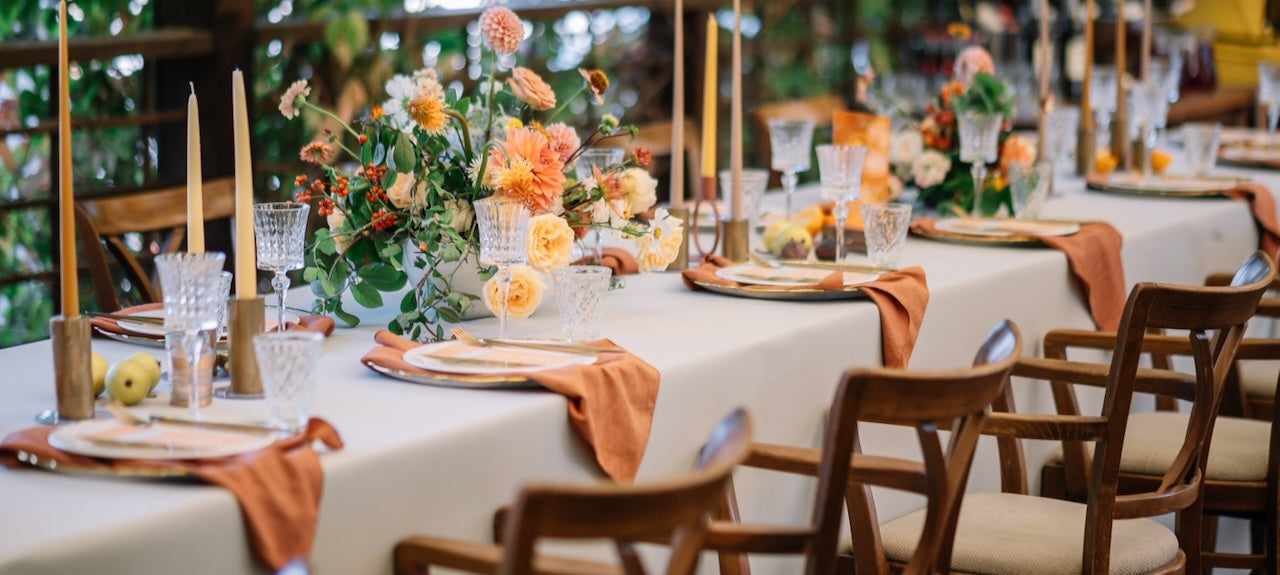 White tablecloth, with wood log slice with candles and white baby breath flowers in glass jars