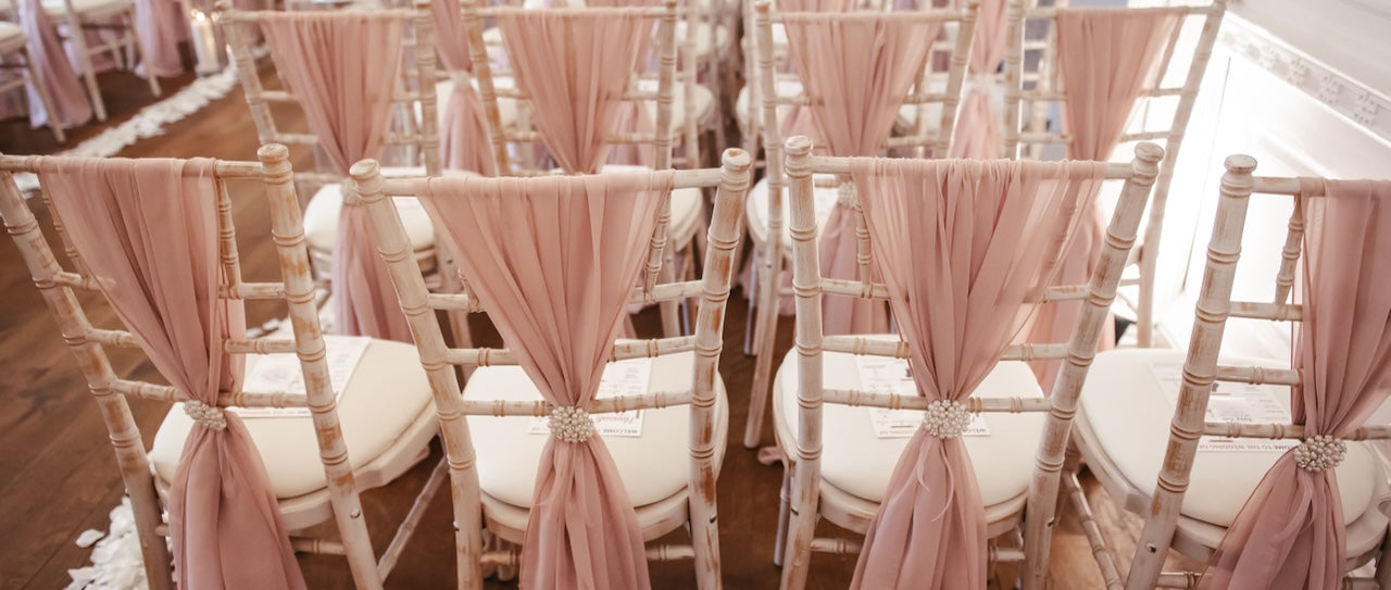 champagne glasses half filled with rose wine and berries, lined up on white tablecloth