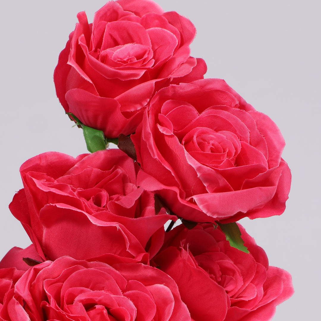A close-up of several artificial hot pink roses with green stems against a plain light gray background.