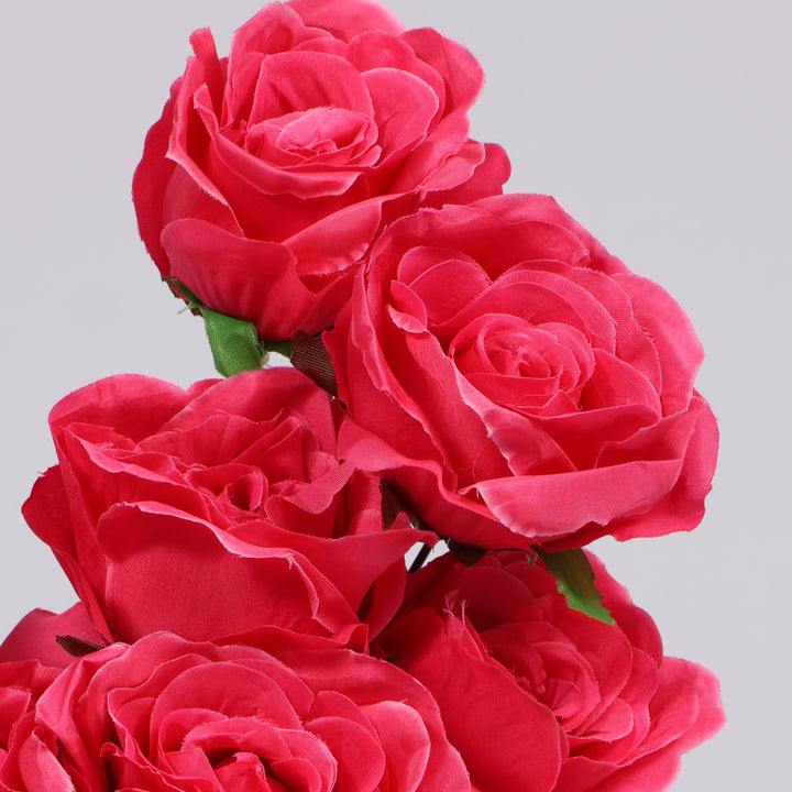 A close-up of several artificial hot pink roses with green stems against a plain light gray background.