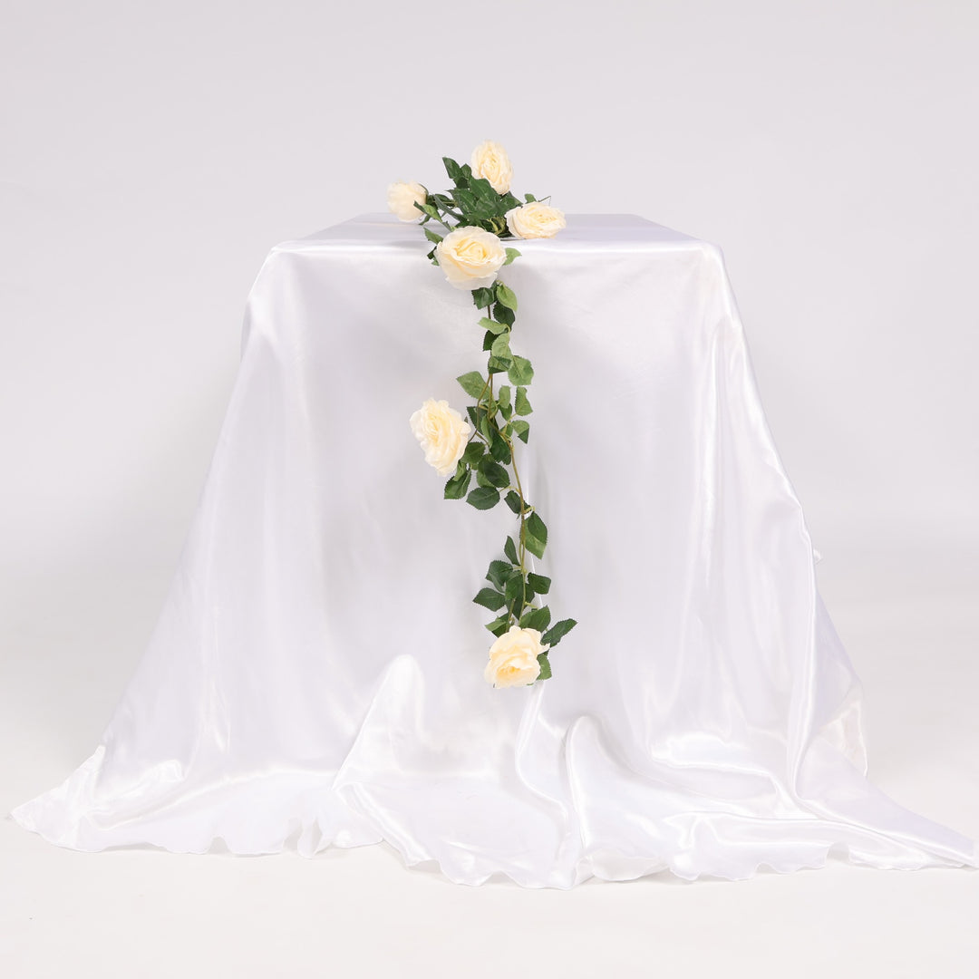 Decorative floral garland on a white draped tablecloth against a plain background