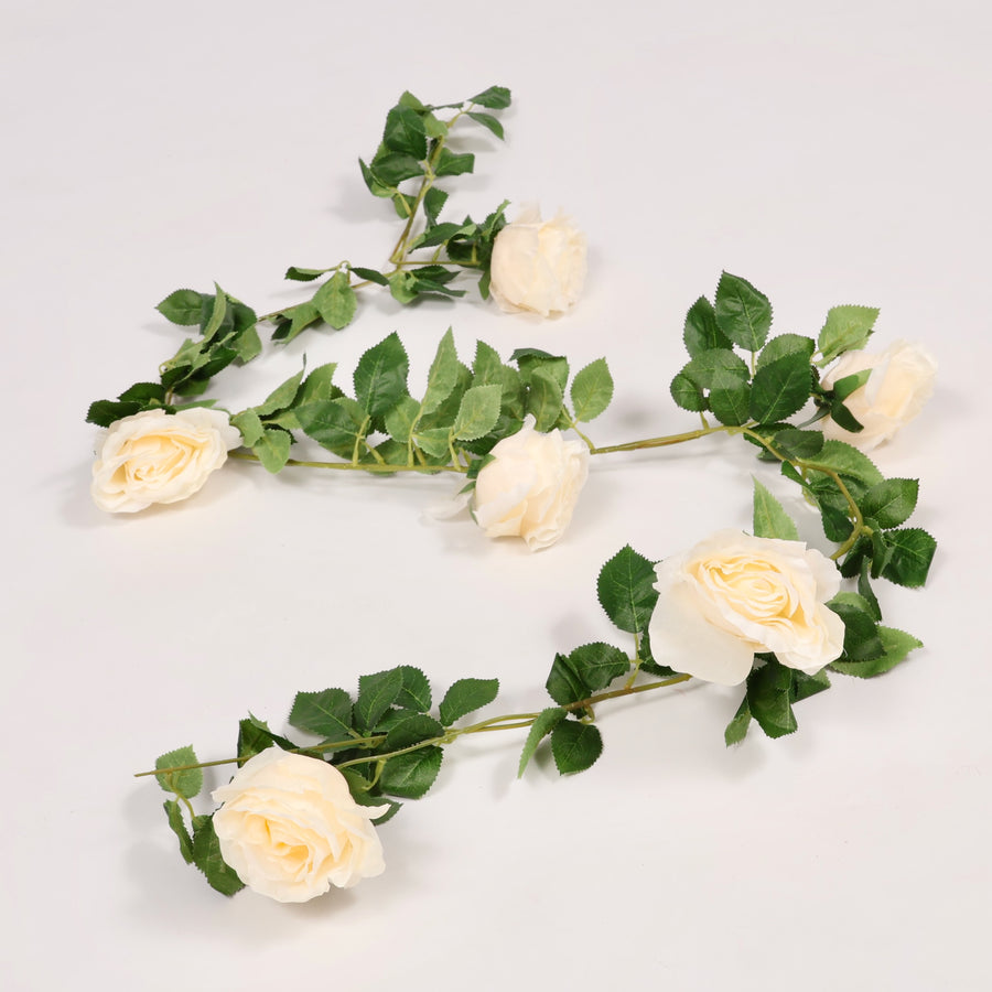 Artificial flower garland with cream roses and green leaves on a light gray background