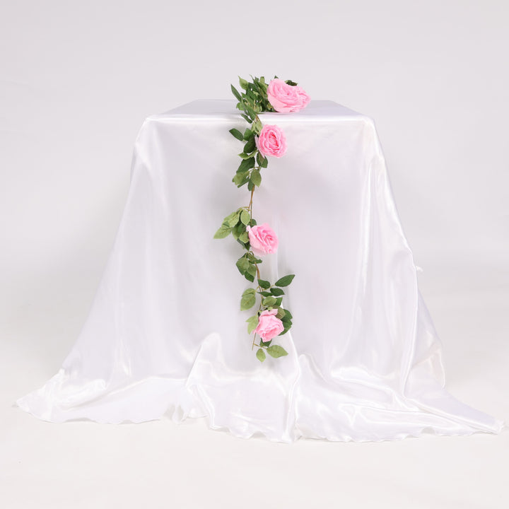 Decorative floral garland with pink roses on a white fabric background