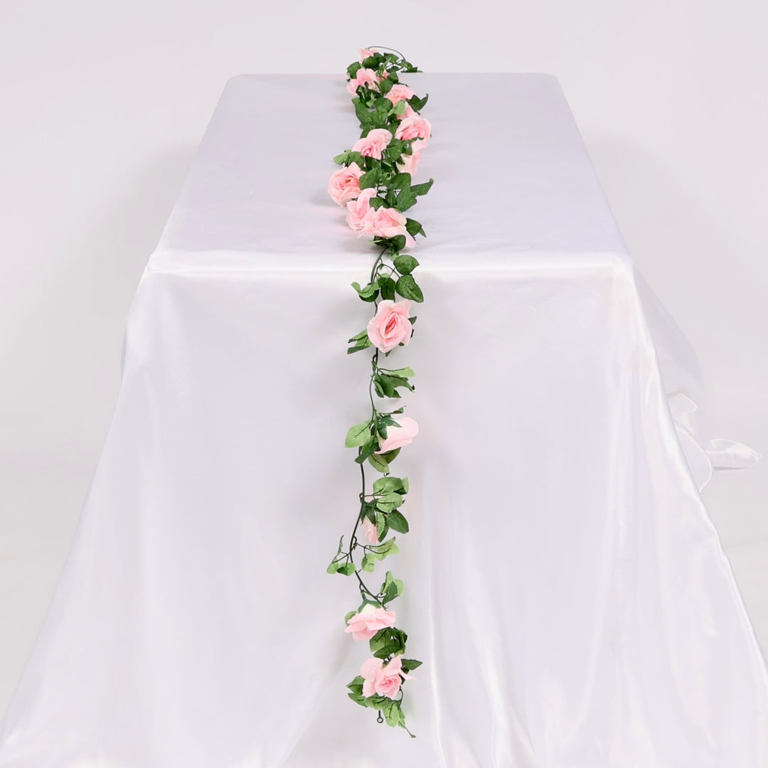 Pink floral garland on a white tablecloth with a white background