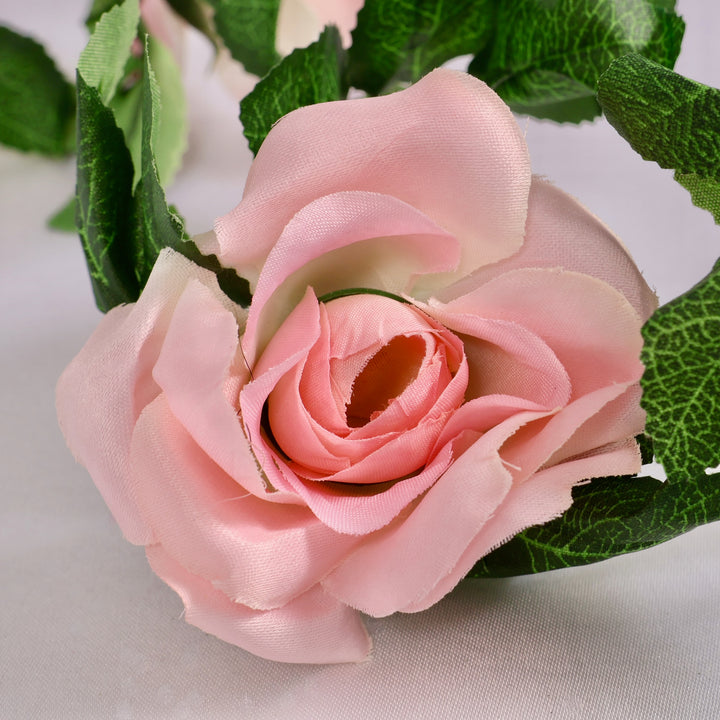 Close-up of a pink rose with green leaves on a light background