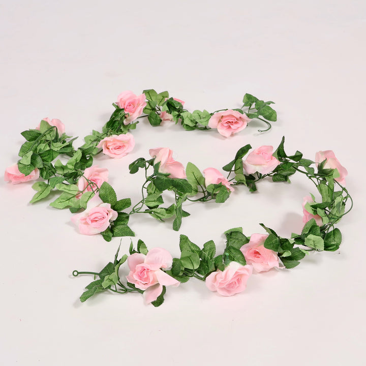 Artificial arrangement of pink flowers and green leaves on a light gray background