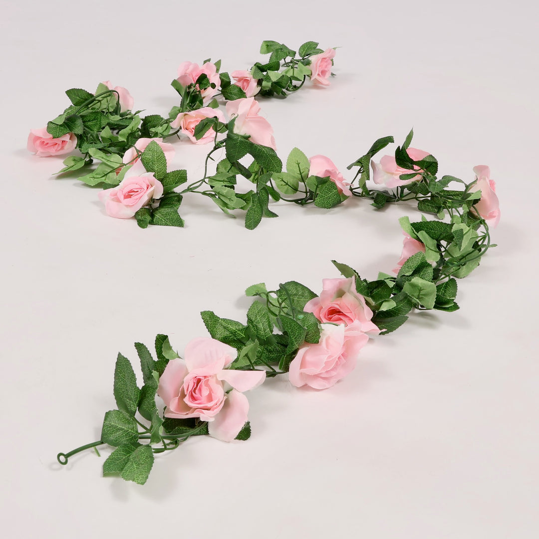 Floral garland with pink flowers and green leaves on a light gray background
