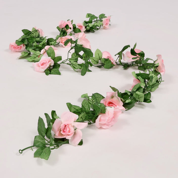 Floral garland with pink flowers and green leaves on a light gray background