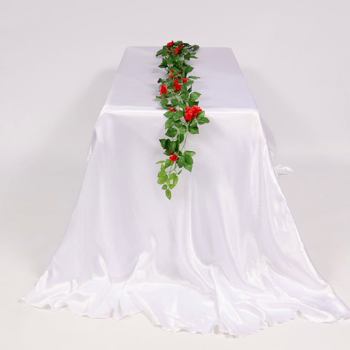 White tablecloth with a red floral vine as table runner on a plain background