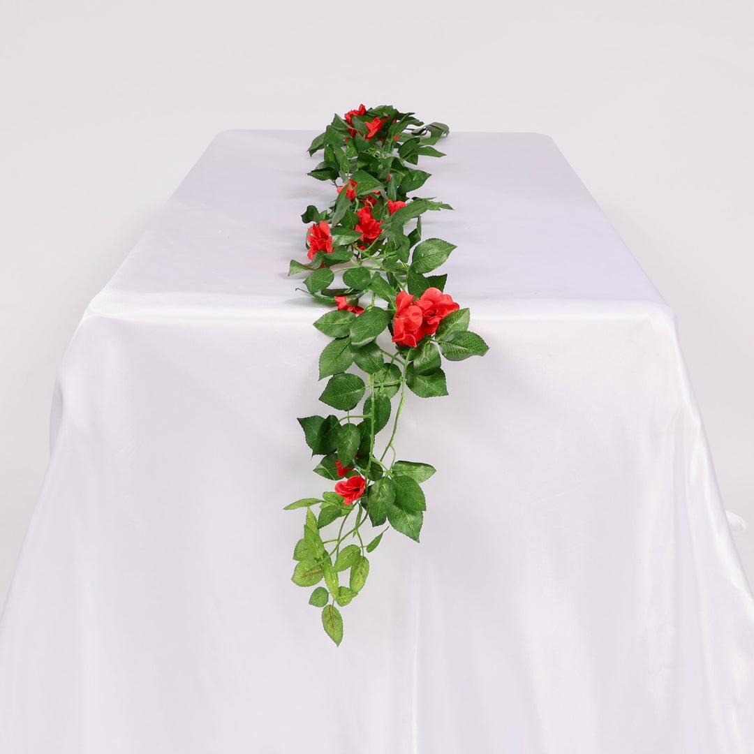 Artificial green vine with red flowers on a white table with white background