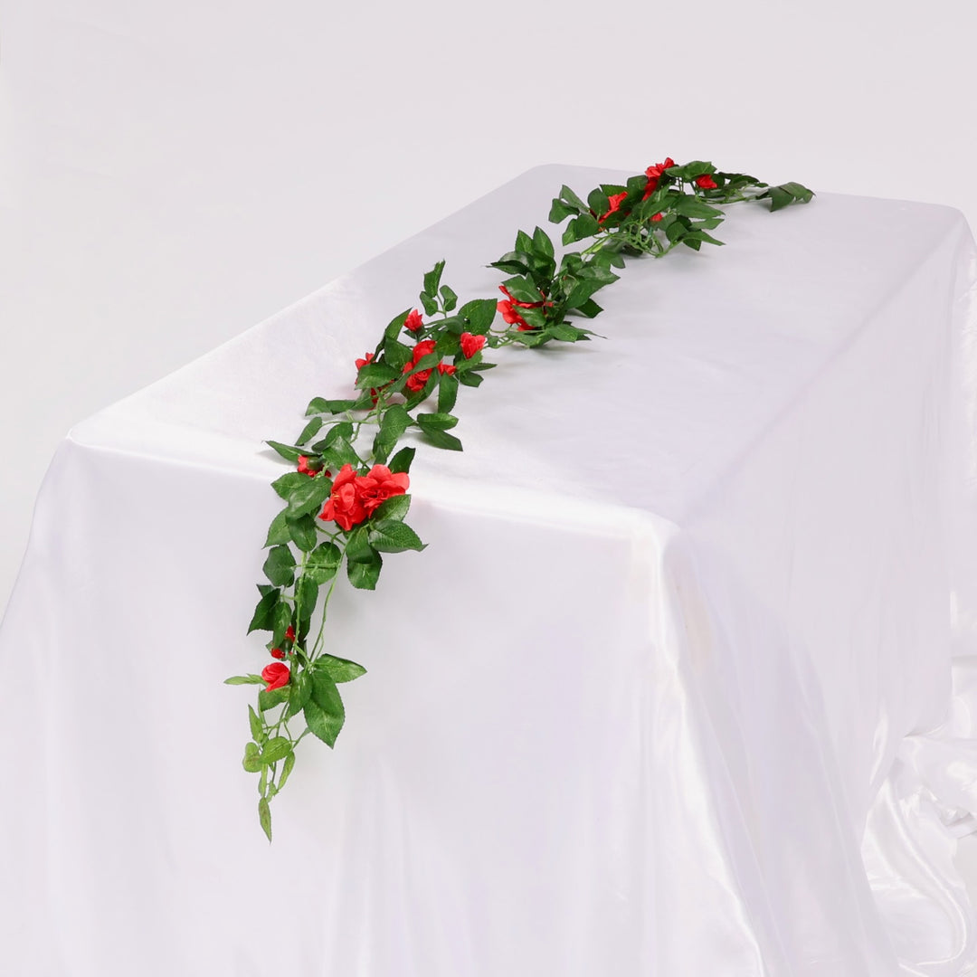 Artificial green vine with red flowers on a white tablecloth