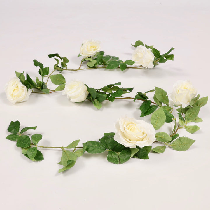 Artificial flower garland with white flowers and green leaves on a light gray background