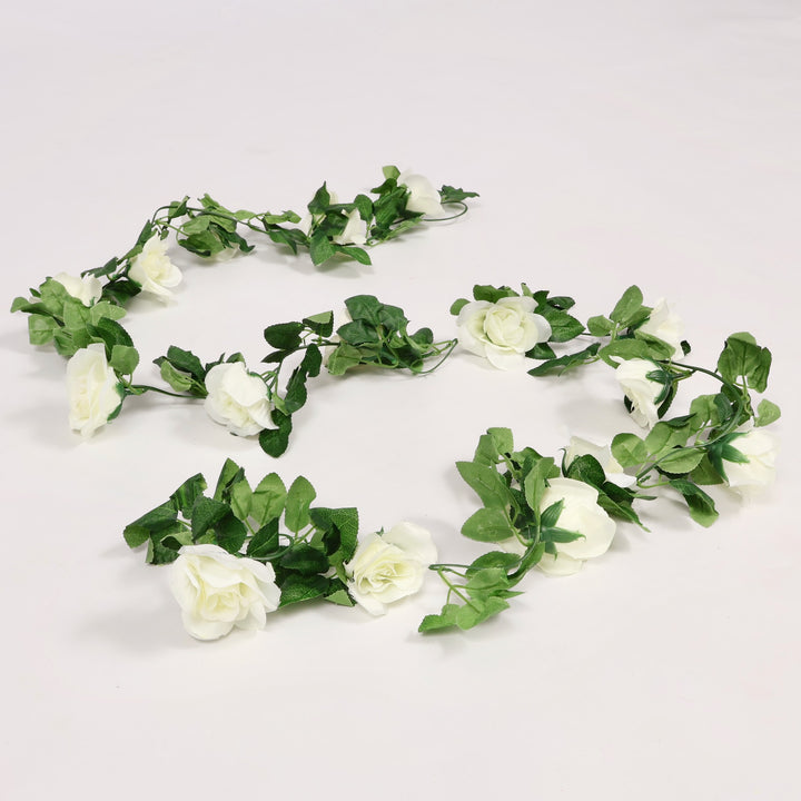 Artificial flower garland with white flowers and green leaves on a light gray background
