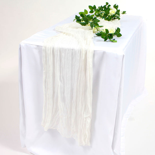 White cheesecloth Runner on white tablecloth with white rose vine 