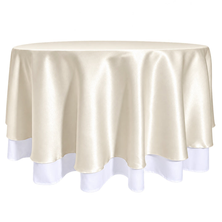 A round tablecloth in ivory satin, draped over a round table with a white underlay, visible at the bottom edge.