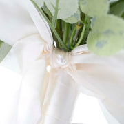Close up of white ribbon bow on ribbon wrapped steams with perl in centre of bow