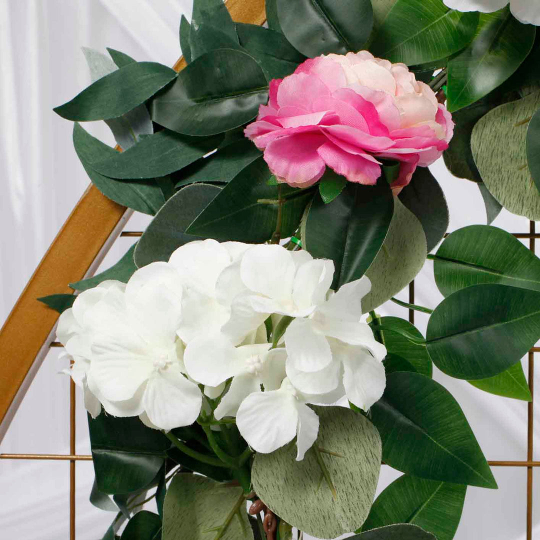 close up of small white flowers and pink/peach flowers with green leaves.